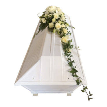 Begravningsblommor med vita rosor, brudslöja samt murgröna liggandes på en vit kista som kistdekoration.
