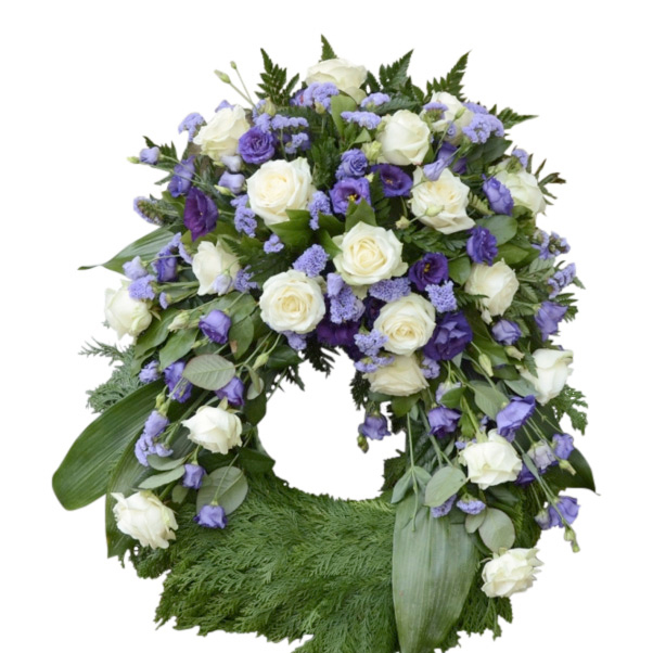Lavendel begravningskrans med vita rosor och lila prärieklockor. Blommorna är runt hela kransen förutom nedersta delen av kransen. Kransen är i mitten av en vit bakgrund och är en begravningsblomma.