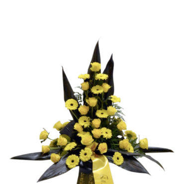 Sorgdekoration med begravningsblommor i AIK färger. Det vill säga i gult och svart. Buketten har gula rosor och minigerbera i mitten och svarta blad som sticker ut runt blommorna.Längst ner på buketten finns det ett band som hänger ner i AIK färger.
